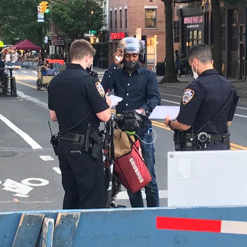 Police stop a delivery rider on Fifth Avenue in Park Slope on Sunday afternoon. Photo: Doug Gordon