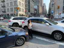 A pedestrian squeezes between cars blocking the box on Canal Street.