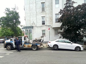 An NYPD tow truck removes a legally parked Brooklynite's car so that cops could park there. Photo: Jody Rosen